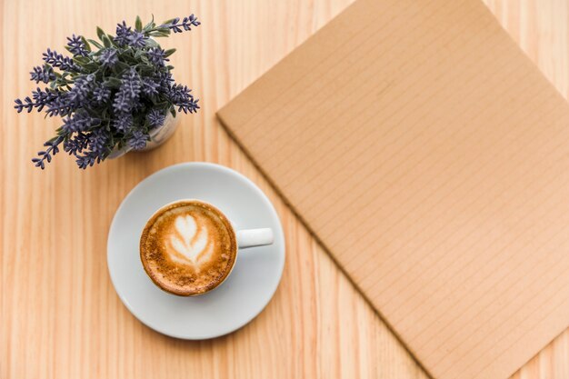 Café con leche con flor de lavanda y cuaderno sobre fondo de madera