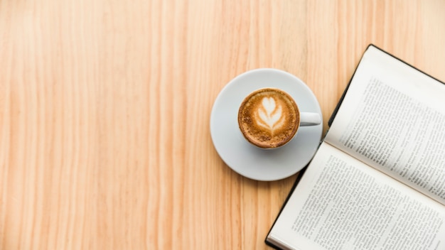 Café con leche y libro abierto en la superficie de madera