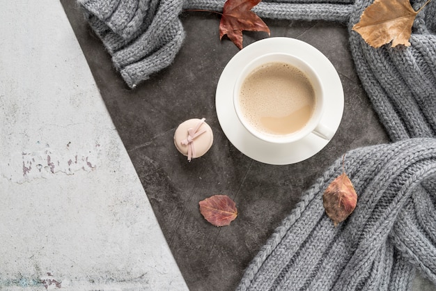 Café con leche y suéter caliente en superficie cutre.