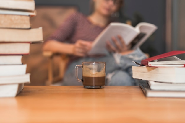 Café y libros cerca de mujer leyendo