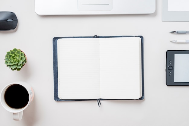 Café y planta cerca de un cuaderno abierto