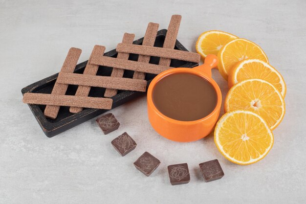 Café, rodajas de naranja, chocolate y galletas en la superficie de mármol