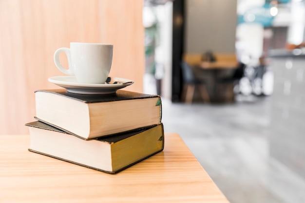 Café sobre libros sobre mesa de madera en tienda de café