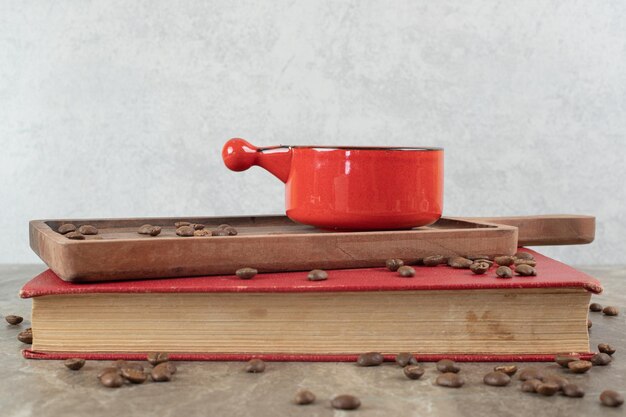 Café sobre tabla de madera con granos de café y libro