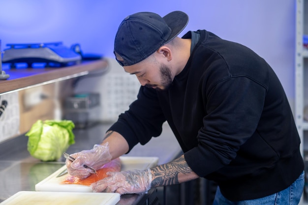 Foto gratuita café de sushi. chef de sushi cortando pescado y haciendo sushi