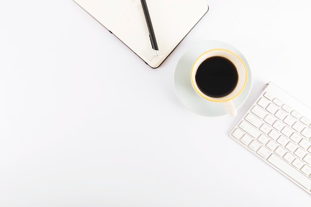 Café entre el teclado y el cuaderno