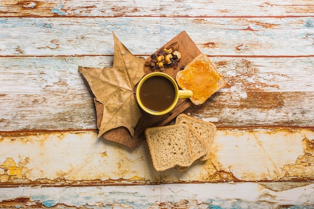 Café y tostadas cerca de hojas y pasas