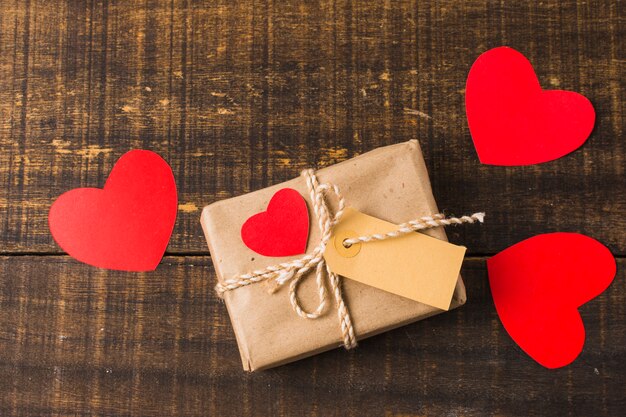 La caja actual envuelta y el recorte de papel del corazón forman con la etiqueta en blanco sobre fondo de madera