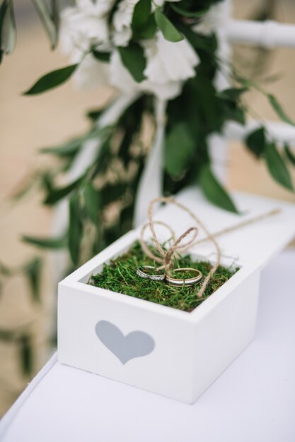 Caja blanca con diseño de corazón y anillos de boda dentro