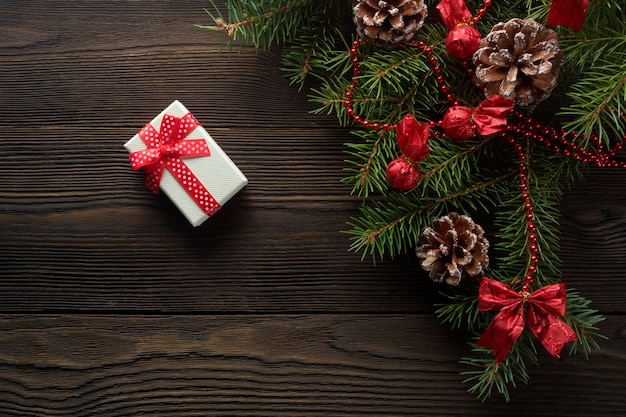 Caja blanca con un lazo rojo sobre una mesa de madera con adorno de navidad
