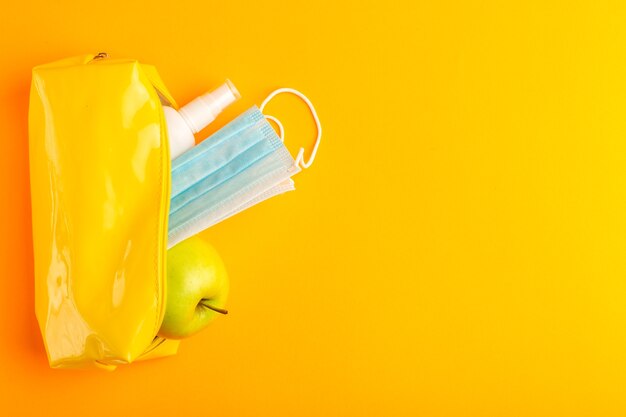 Caja de bolígrafo amarillo vista superior con spray apple y máscara en la superficie naranja