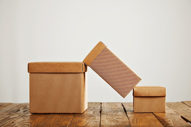 Una caja de cartón alta en equilibrio sobre dos cajas similares con tapas en un ambiente de estudio aislado en blanco