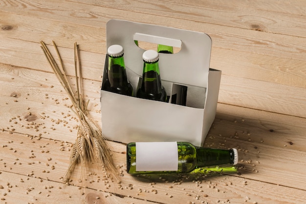 Caja de cartón de cerveza y espigas de trigo sobre fondo de madera
