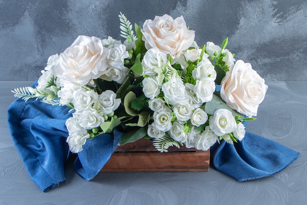 Una caja de flores blancas con toalla, sobre la mesa blanca.