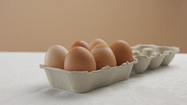 Caja con huevos marrones en estudio sobre mesa blanca