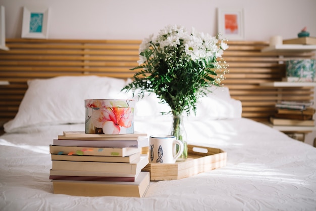 Foto gratuita caja de libros cerca de la bandeja con ramo