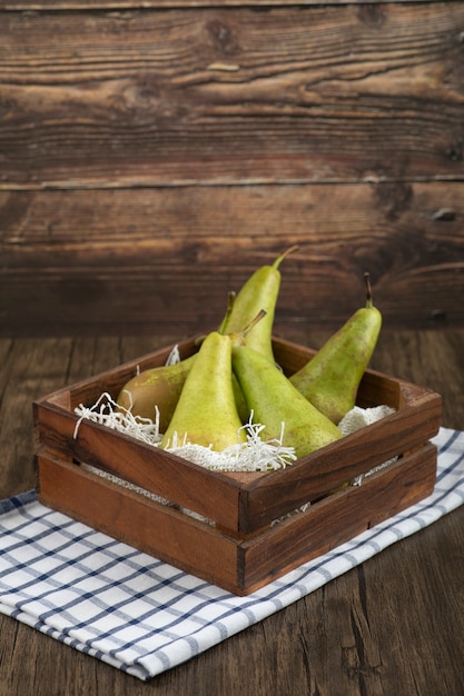 Caja de madera de deliciosas peras maduras sobre fondo de madera