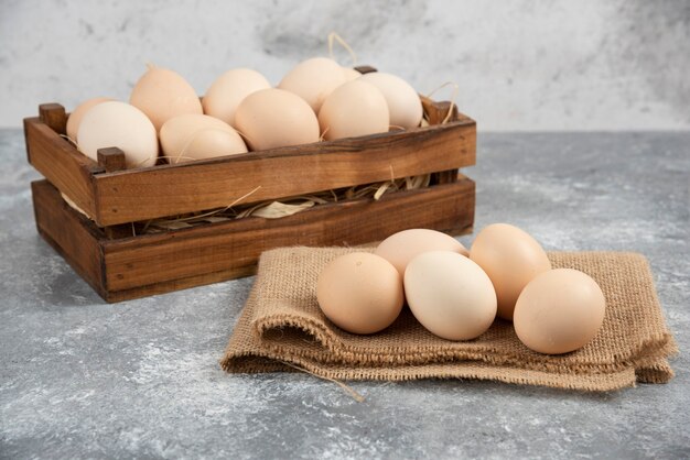 Caja de madera de huevos crudos orgánicos sobre superficie de mármol.