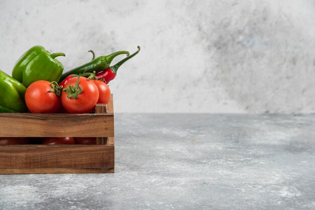 Caja de madera llena de verduras frescas en mármol.