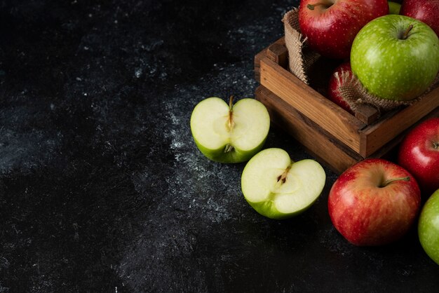 Caja de madera de manzanas orgánicas frescas sobre superficie negra. .