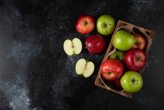 Caja de madera de manzanas orgánicas frescas sobre superficie negra. .