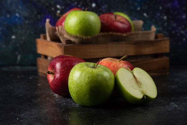 Caja de madera de manzanas orgánicas frescas sobre superficie negra. .