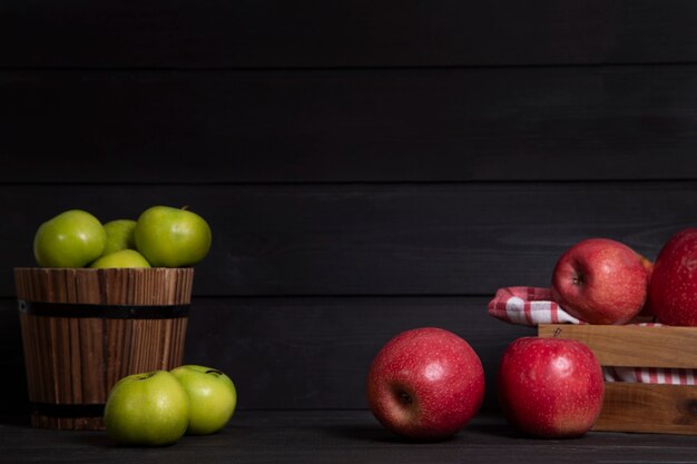 Caja de madera de manzanas rojas y manzanas verdes sobre fondo oscuro. Foto de alta calidad