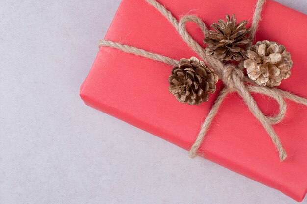 Caja de Navidad roja con tres piñas en blanco.