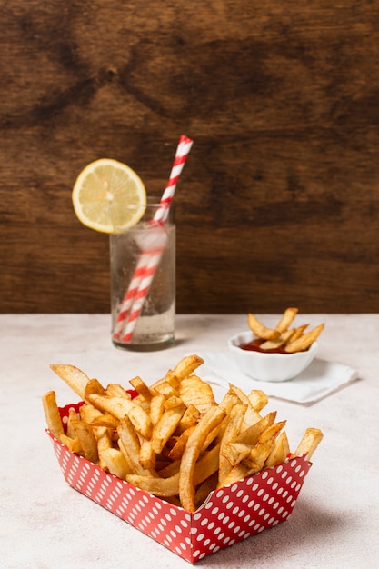 Foto gratuita caja de papas fritas en mesa blanca