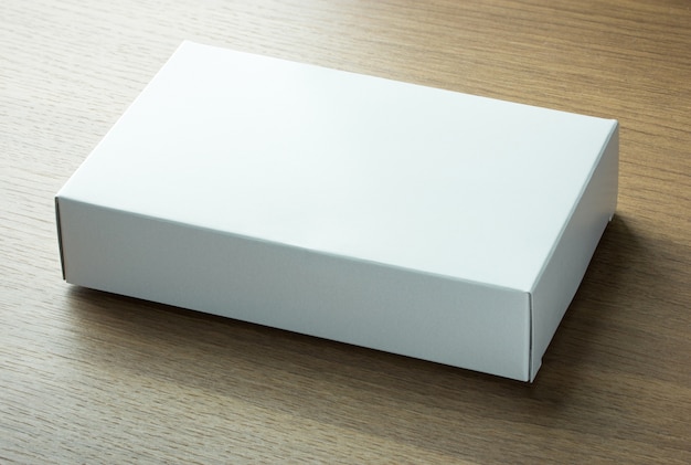 Caja de papel blanco en blanco sobre fondo de madera oscura