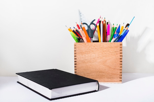 Caja con papelería cerca del libro