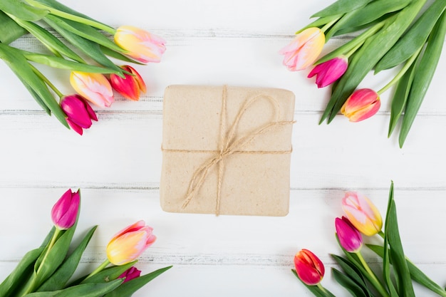 Caja de regalo alrededor de ramos de tulipanes.