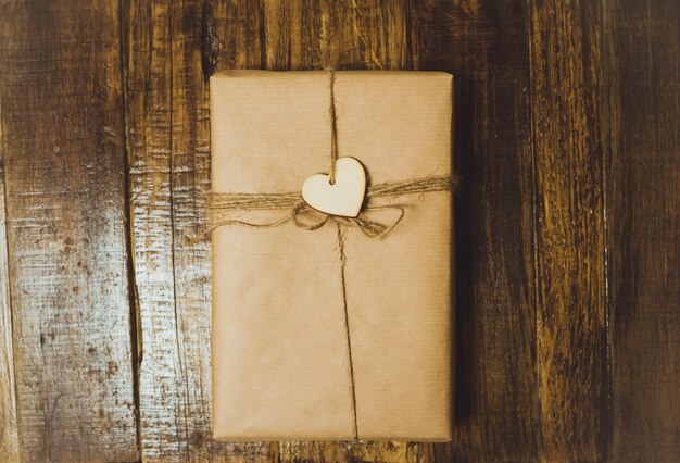 Caja de regalo artesanal con corazón rojo en una mesa de madera Vista superior