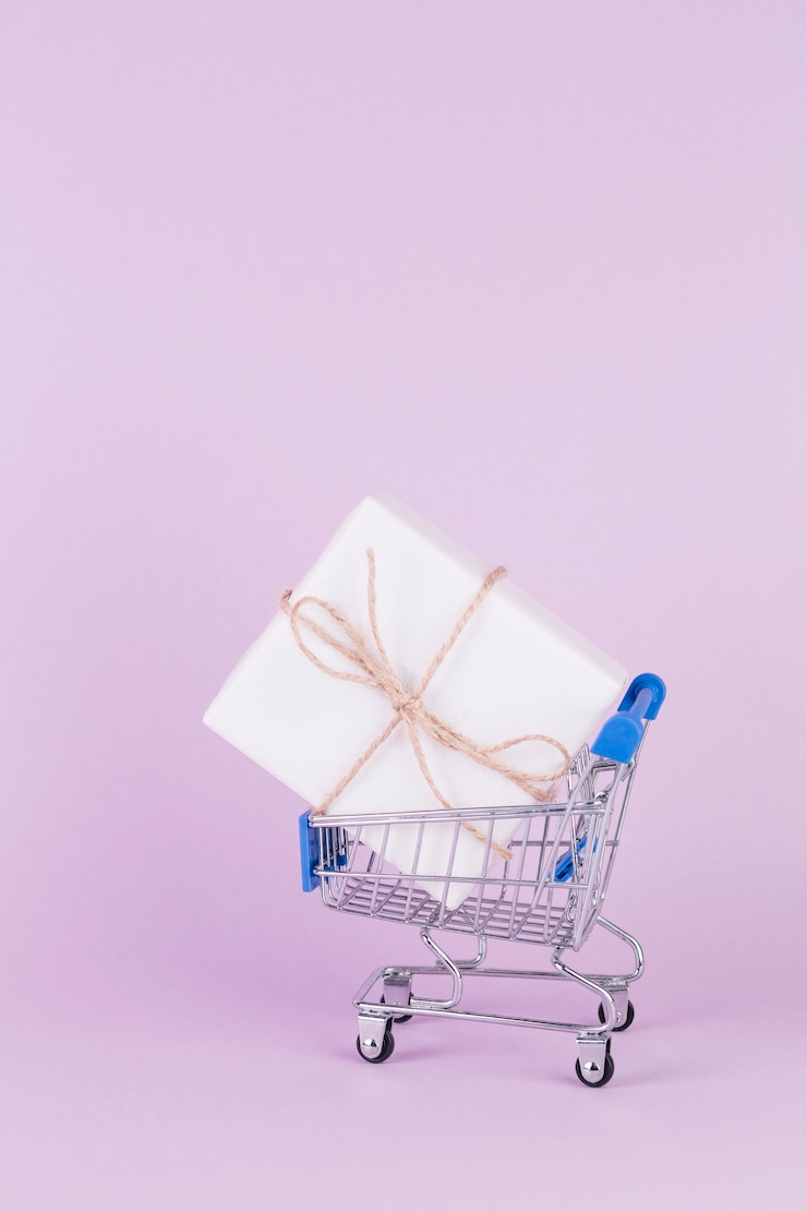 Foto gratuito caja de regalo atada con una cuerda en carrito de compras en fondo rosa