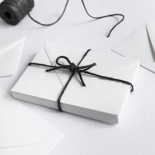 Caja de regalo blanca atada con una cuerda negra sobre fondo blanco