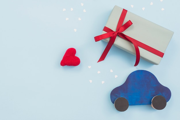 Caja de regalo con carro de juguete y corazón rojo.