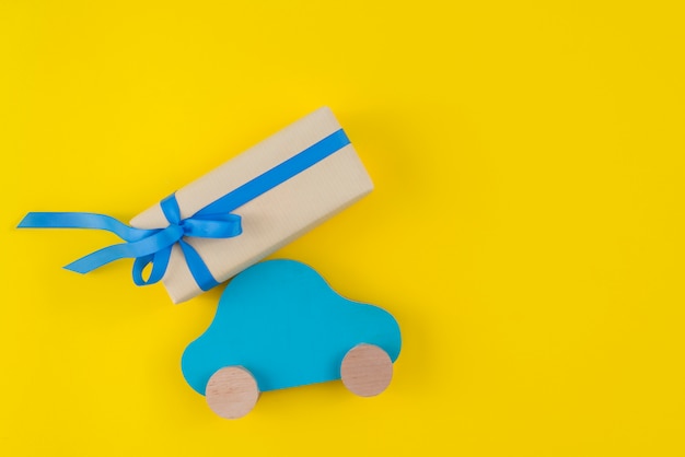 Caja de regalo con carro de juguete en mesa amarilla.