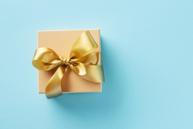 Caja de regalo con cinta dorada sobre fondo brillante