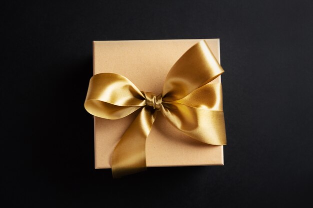 Caja de regalo con cinta dorada sobre superficie oscura