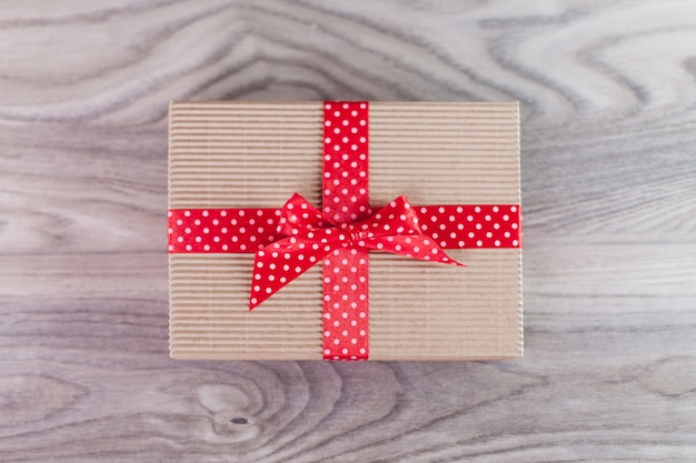 Caja de regalo con cinta roja sobre madera