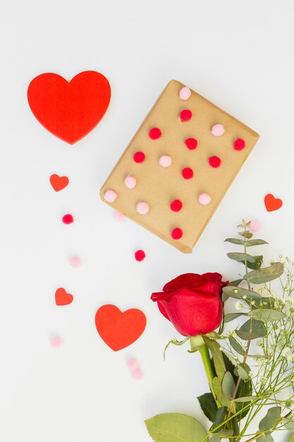 Caja de regalo con corazón y rosa roja en mesa