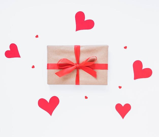 Caja de regalo con corazones rojos en mesa de luz