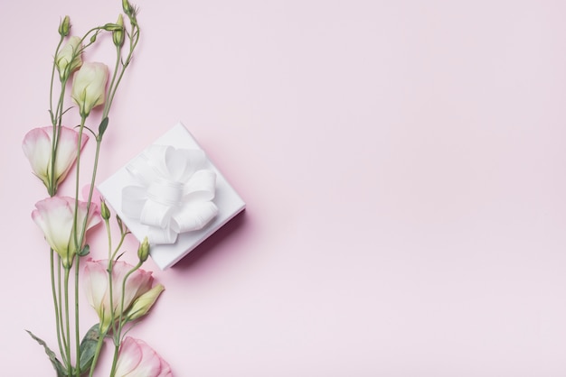 Caja de regalo decorada blanca con flores de eustoma sobre fondo rosa