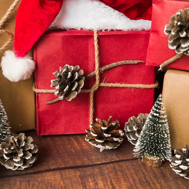 Caja de regalo decorada cerca de ganchos y gorro navideño.