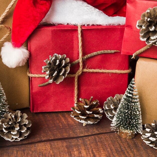 Caja de regalo decorada cerca de ganchos y gorro navideño.