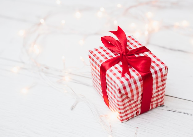 Caja de regalo en envoltura cerca de luces de hadas iluminadas