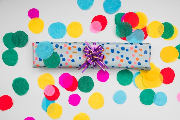 Caja de regalo envuelta del lunar con el papel coloreado cortado circular en el fondo blanco