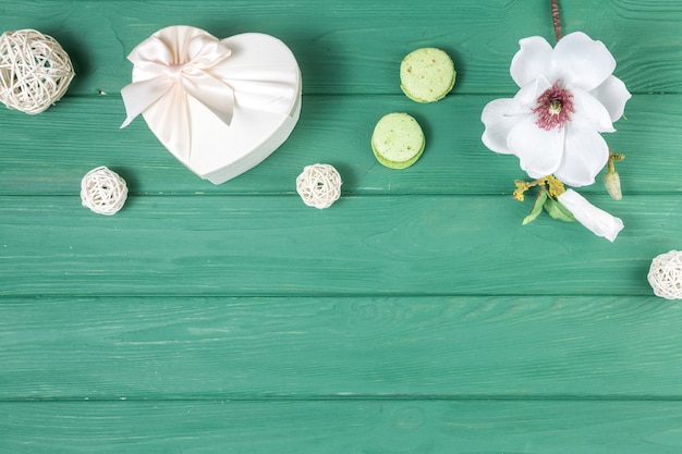 Caja de regalo en forma de corazón con flores y macarrones.