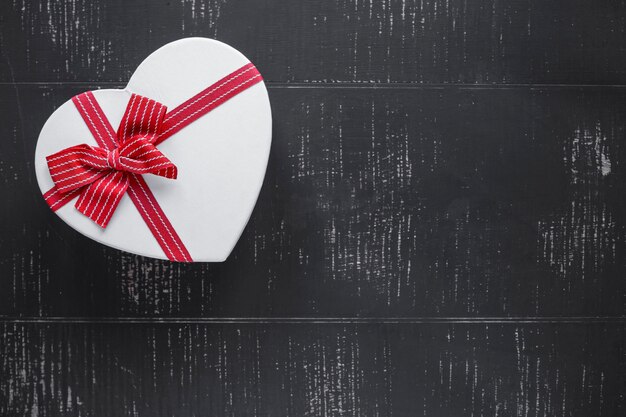 Caja de regalo en forma de corazón en fondo negro