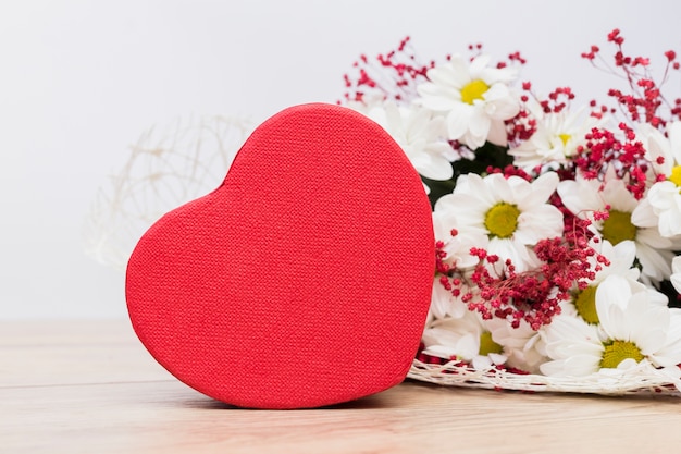 Caja de regalo en forma de corazón con ramo de flores en la mesa